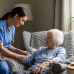 Nurse providing skilled nursing care at home to elderly patient, assessing health and coordinating personalized care in a comfortable living room setting.